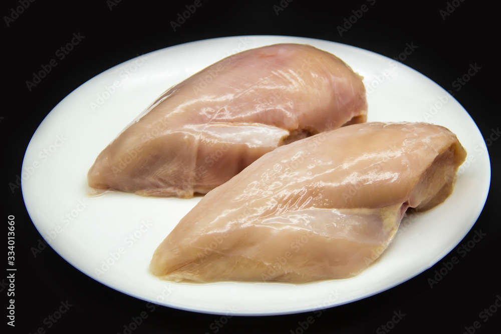 Fresh raw chicken fillet on a white plate against a background. Chicken fillet without non-GMO. Raw chicken breasts on the plate