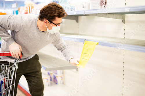 Mann vor einem leeren Regal in einer Drogerie, Toilettenpapier ist ausverkauft  photo