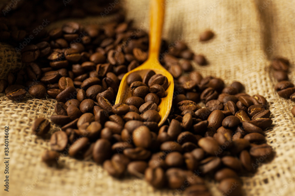 scattered Coffee beans spilling from a burlap bag and a scoop scattered Coffee beans spilling from a burlap bag and a scoop