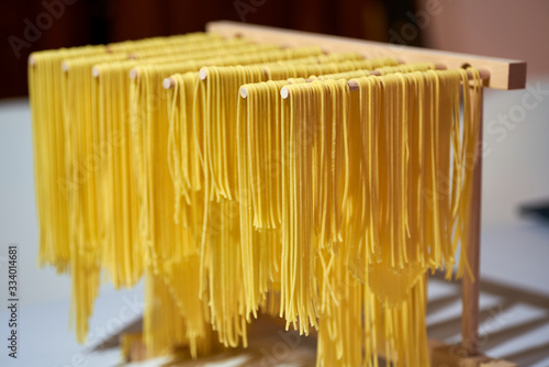 Selbst gemachte Spaghetti Nudeln aus Hartweizengrieß Semola auf Holzständer zum Trocknen aufgehängt