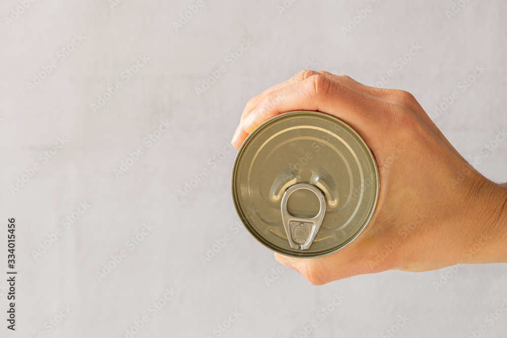 Hand holding aluminium tin can isolated on a grey background. Hand holding aluminium tin can isolated on a grey background.