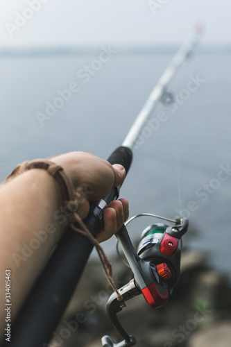 fisherman hand holds spinning directed towards the water