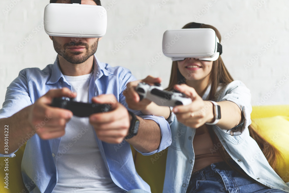 Closeup view of young smiling couple in VR glasses playing video game on the couch Closeup view of young smiling couple in VR glasses playing video game on the couch