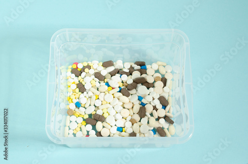 Container with pills. Multicolored and white pills in a transparent box. Pills on a blue background. photo