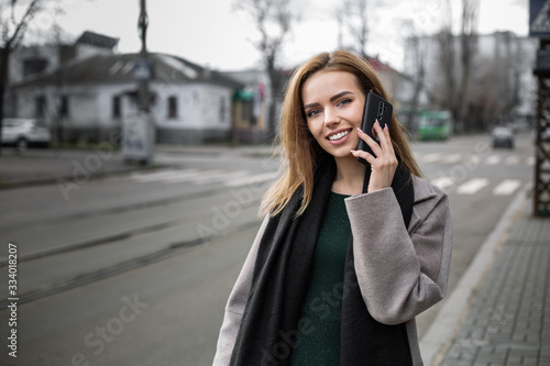 Girl talking on a smartphone at a tram stop.