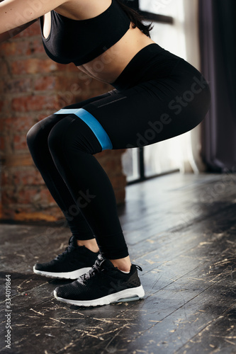 Girl athlete doing sit-UPS with a blue rubber band on the hips. Exercises for the muscles of the thighs.