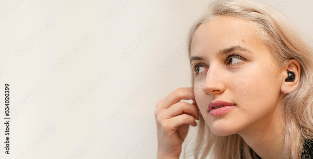 Girl puts on wireless headphones. Modern technologies. Girl puts on wireless headphones. Modern technologies.