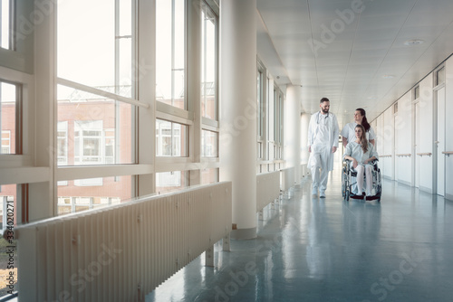 Fotomurale Doctor, nurse, and patient in wheelchair on hospital corridor