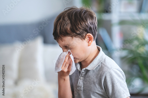 Photos Sick boy blowing nose into tissue, Unhealthy child suffering from running nose