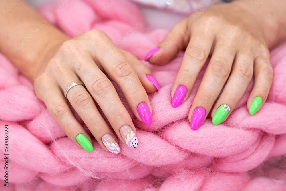 Lots of color gloss manicure hands has different blotches in pink background.
