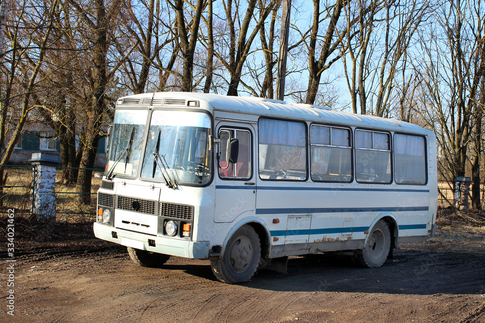 White-blue empty bus standing on a background of trees