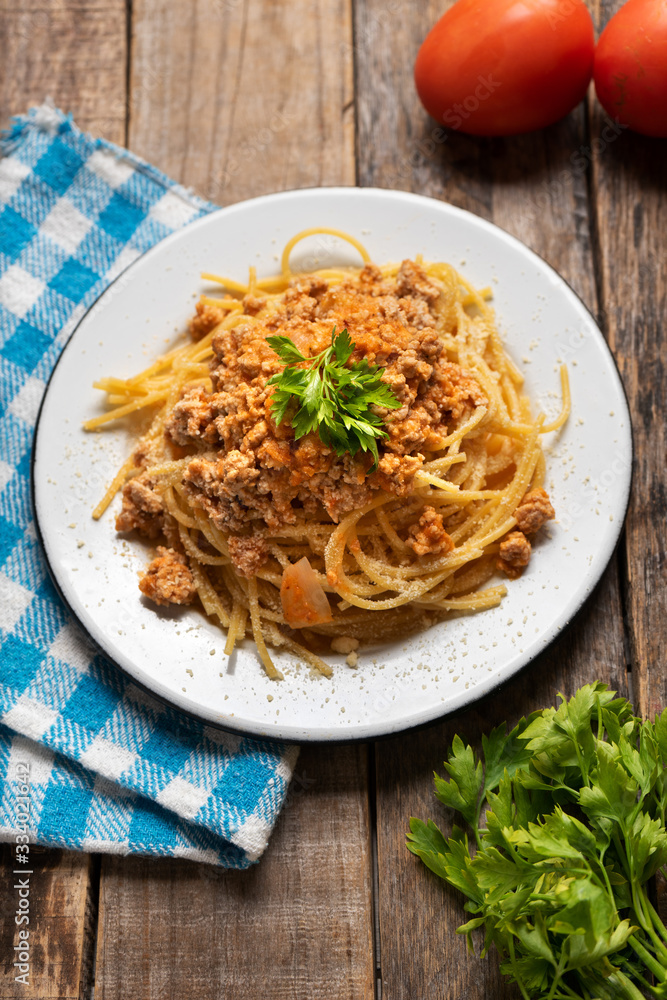 Spaghetti bolognese with parmesan cheese on wooden background
