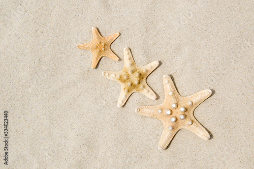 Top view of three starfish on sandy beach. Summer vacation concept on a sunny day