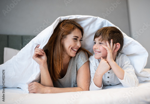 Mother and son on the bed covered by a blanket.