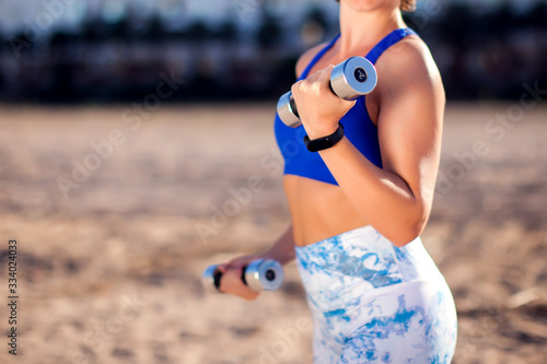 Woman training with dumbbells outdoor. People, fitness and healthcare concept