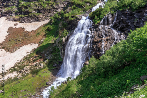 Beautiful scenic landscape of Imeretinskiy waterfall in Caucasus mountains  Karachai-Cherkess Republic. Imeretinka river waterfall at summer in sunlight with splashes and blue sky.