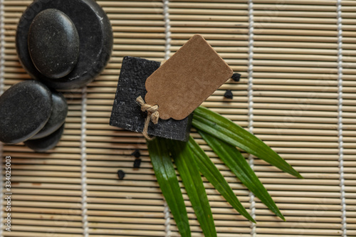 charcoal coal carbon black soap bar on a raw wood bamboo background lava stone spa skin care hygiene concept  photo