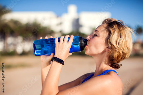 Woman drinking water while workout outdoor. People, technology and healthcare concept