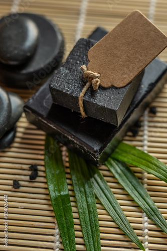bar block of black carbon charcoal coal soap on a bamboo background with lava stones spa concept