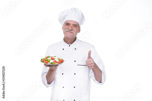 Cooking and professional culinary concept, elderly professional chef in white uniform holds vegetable salad stay isolated white background