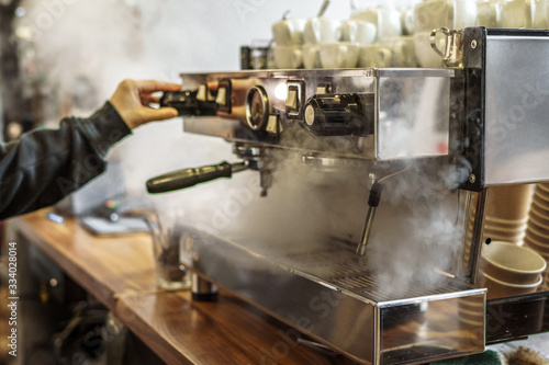 Coffee machine in steam, barista preparing coffee at modern cafe
