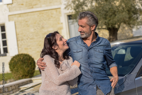 Fotografi Portrait of happy wealthy middle age couple outside of their house