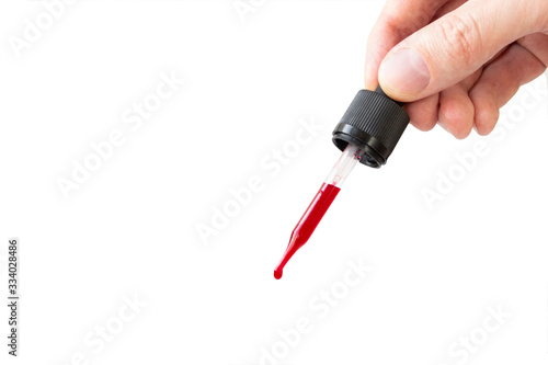 Blood or other red liquid drop from glass pipette isolated on white