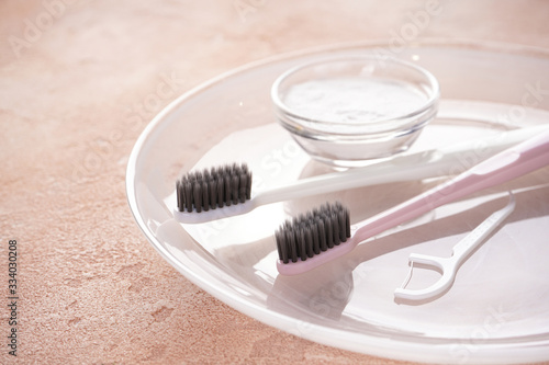 Two toothbrushes, toothpick and toothpaste on a beige background, close-up.