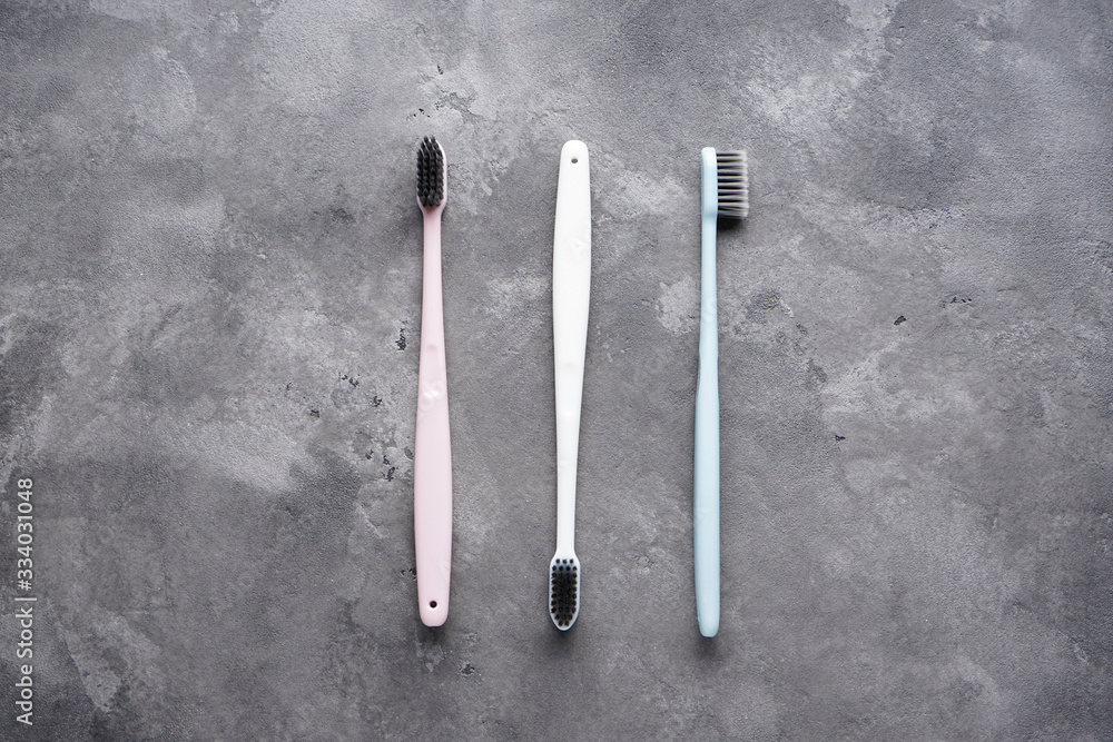 Flat lay composition of multi-colored toothbrushes on a gray background. Flat lay composition of multi-colored toothbrushes on a gray background.
