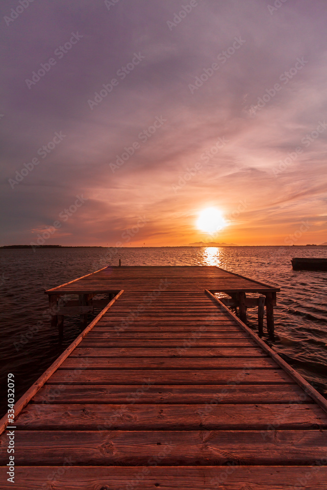 Wooden pier on a warm light during sunset, with violet and orange sky