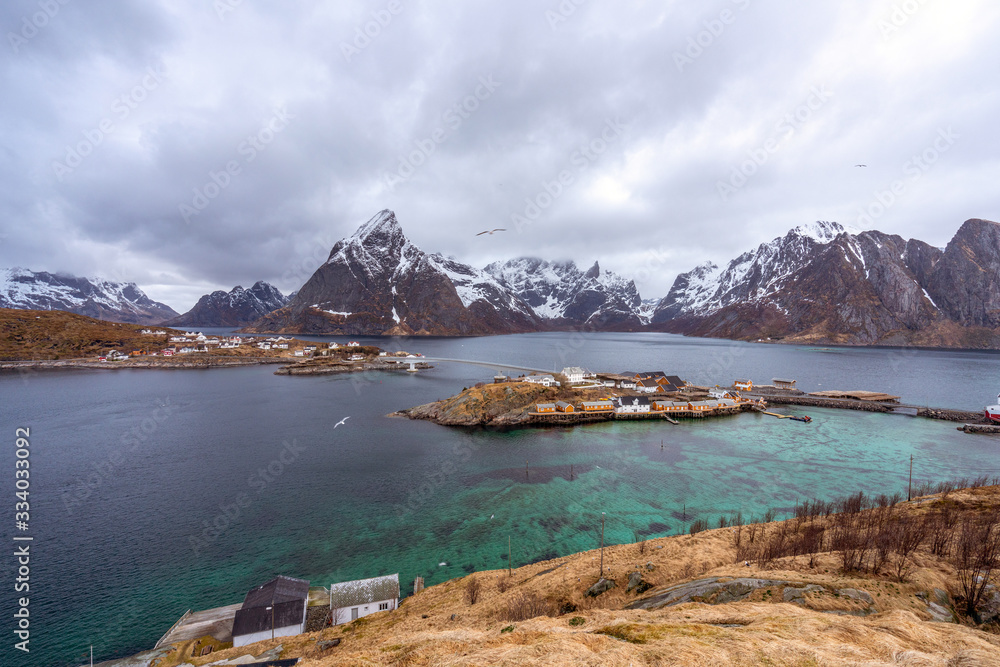 Sakrisoy in Lofoten islands in northern Norway during spring. Snow covered mountains and little village in the background. Traveling and arctic concept. Sakrisoy in Lofoten islands in northern Norway during spring. Snow covered mountains and little village in the background. Traveling and arctic concept.