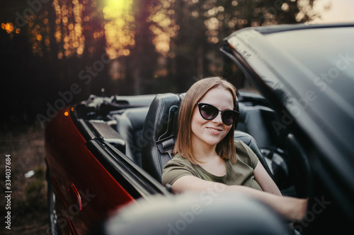 Young woman cabriolet car driver at sunset. Riding a journey driving.