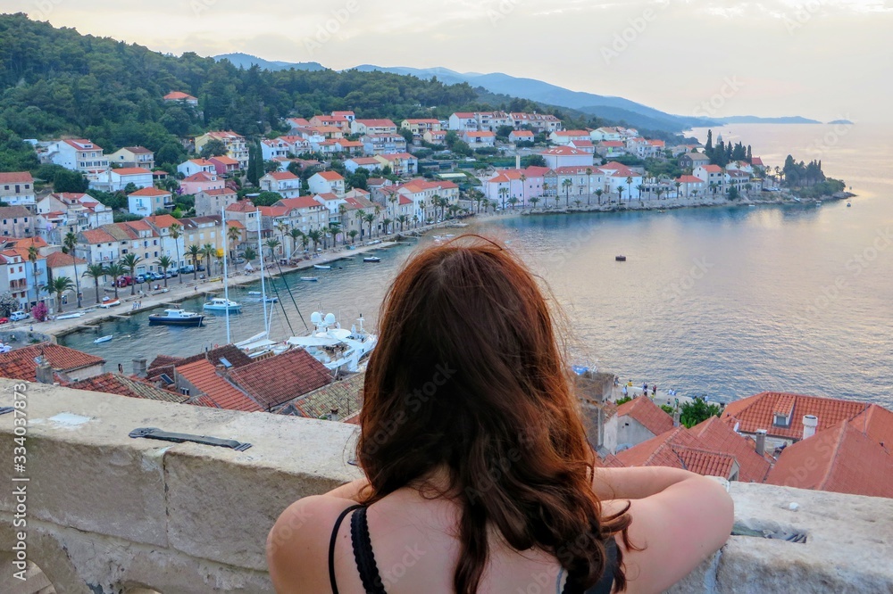 Φωτογραφία A young woman admiring the view from a top the bell tower in the town of Korcula