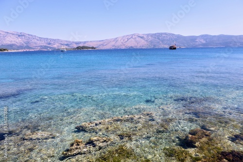 A water level view of the beautiful clear waters of Lumbarda Beach on Korcula Island, Croatia. The peljesac peninsula is in the background. The adriatic sea has some of the most beautiful colors.