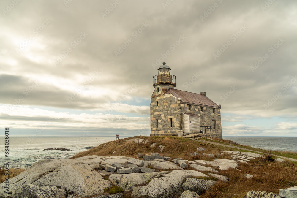 Historic lighthouse, stone building double storey, slate roof and sash window, a walkway around the light room gives the impression of a citadel, sits on a rocky shore of the Atlantic ocean