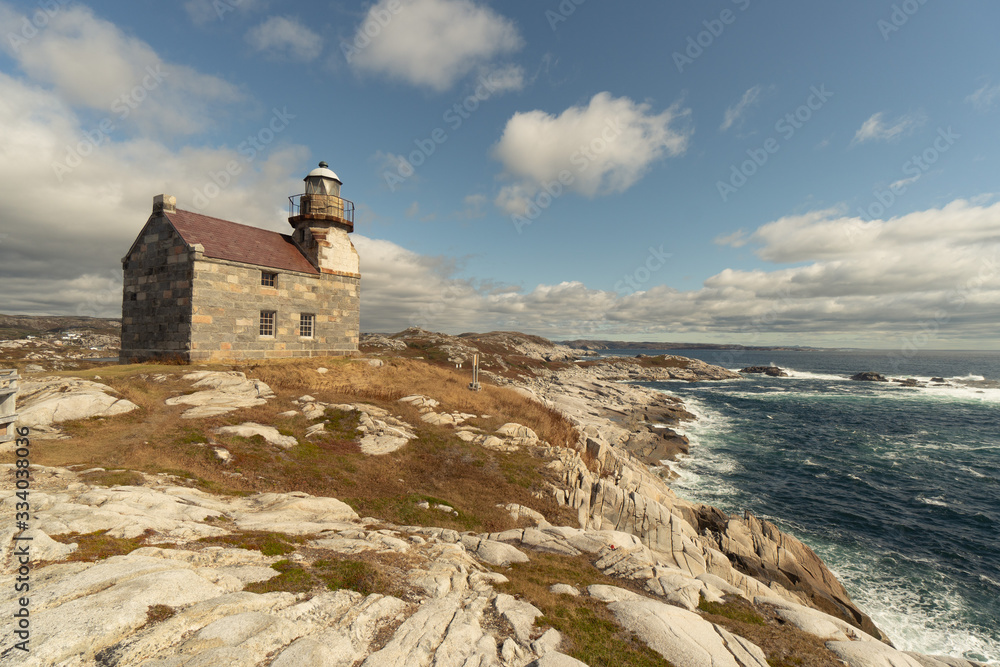Historic lighthouse, ocean view, stone building double storey, slate roof and sash window, a walkway around the light room gives the impression of a castle, sits on a rocky shore of the Atlantic ocean