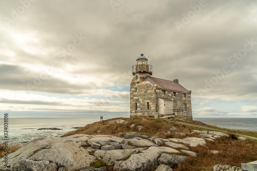 Historic lighthouse, stone building double storey, slate roof and sash window, a walkway around the light room gives the impression of a citadel, sits on a rocky shore of the Atlantic ocean