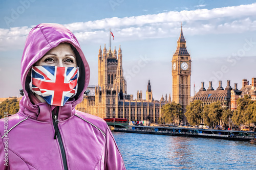 Woman wearing protection face mask with British flag against coronavirus in front the of Big Ben, London, England