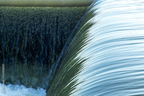 Small dam with water flowing rapids. Seen as lines and patterns with foam. photo