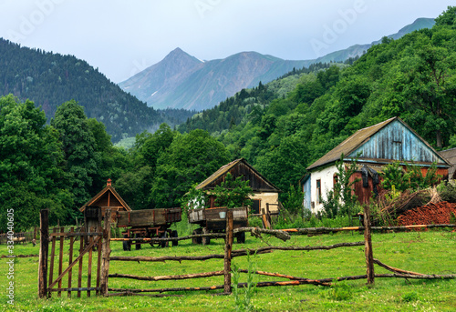 Zakan, Russia. Caucasus Mountains countryside. Rustic house in forest on Lugan mountain peak background. Scenic summer landscape.