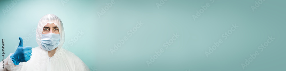 Man in protective suit and medical mask on blue background showing thumbs up