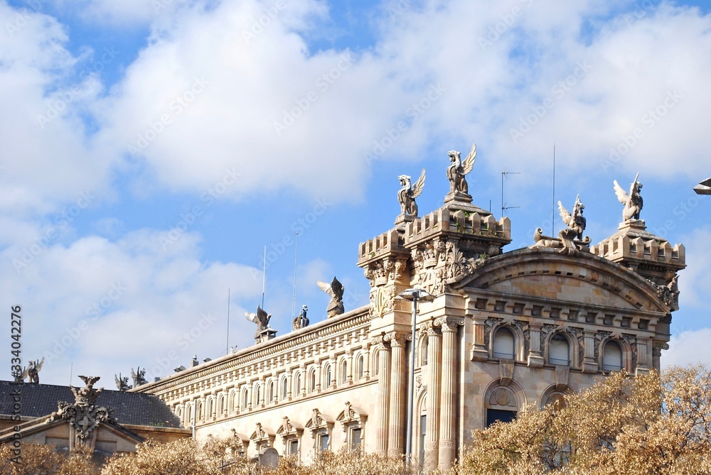 Aduana Building or Duana Nova (New Customs House) at Gate of Peace Port Vell in Barcelona, Spain. Neoclassical design with reliefs of royal crowns, crenels, topped with sculptures of winged lions. 