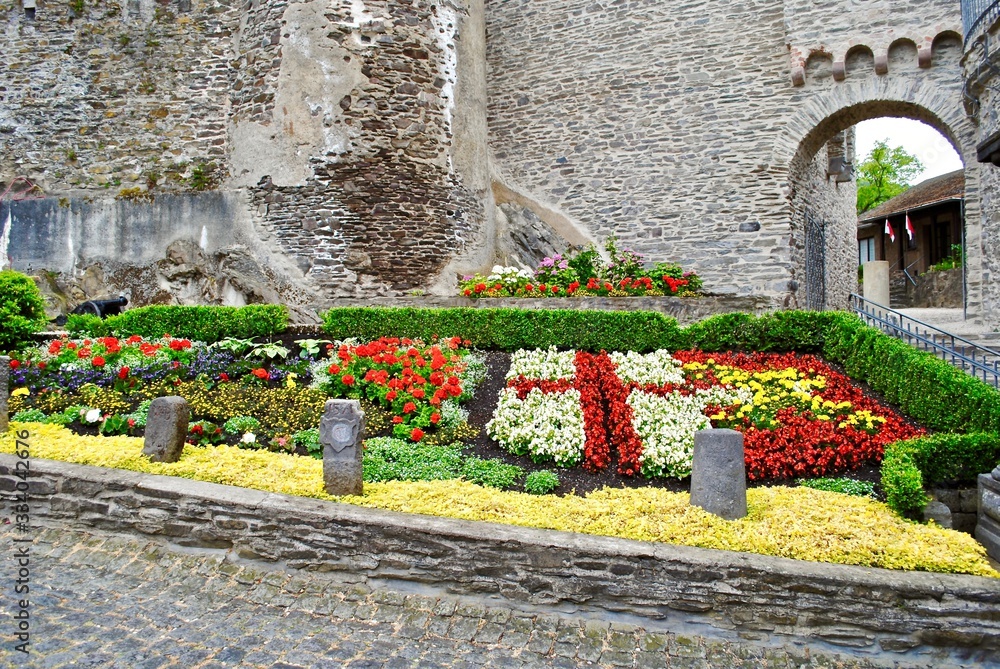 Obraz premium COCHEM, GERMANY - 2014: Flowers planted to represent the seal of Cochem. Exterior of the Cochem Castle (Reichsburg or Burg Cochem), which is a castle in the Rhineland-Palatinate on the Moselle.