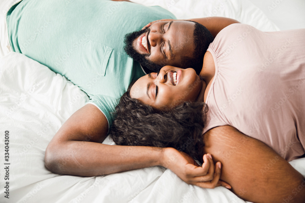 Pleased young couple lying in bed and smiling stock photo
