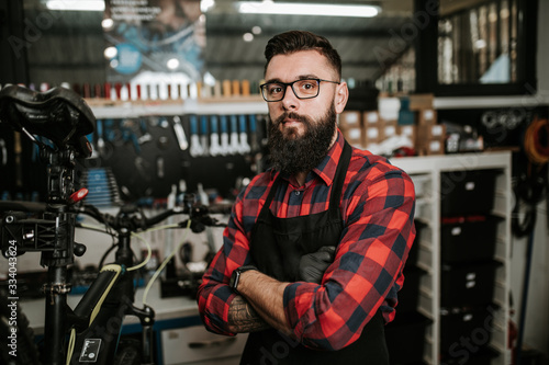 Young beard bicycle mechanic repairing bicycles in a workshop..