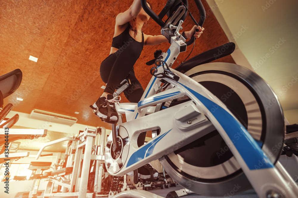 Obraz premium Exercise bike cardio workout at fitness gym. women doing sport biking in the gym for fitness.