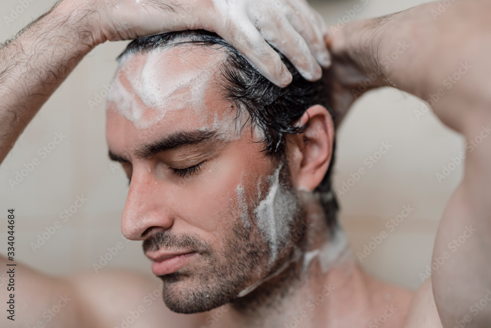 Handsome young single male washing his body and face in bathroom. Handsome young single male washing his body and face in bathroom.
