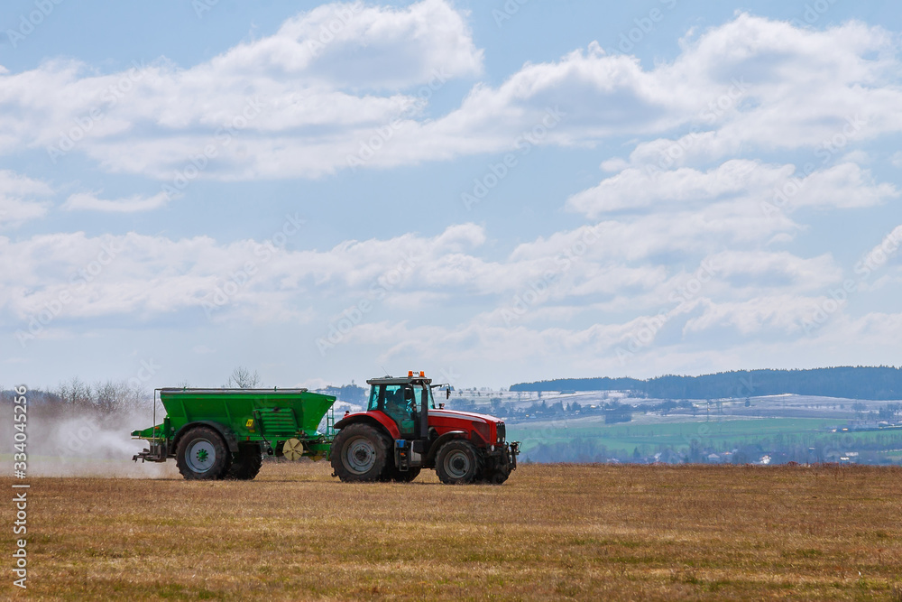 Fototapeta premium Tractor spreading fertilizer on grass field. Agricultural work.
