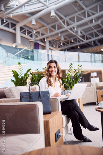 Cheerful young woman using laptop at business center