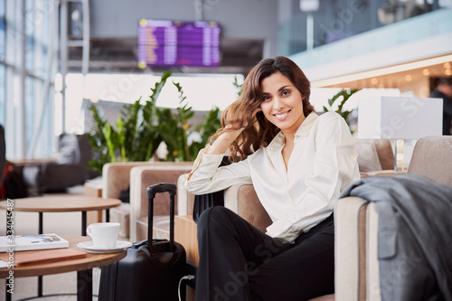 Cheerful pretty lady sitting in chair in airport waiting room